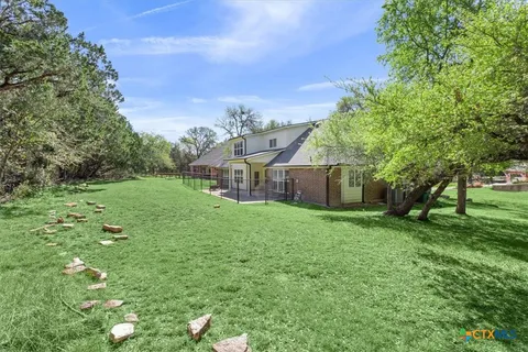 a view of a house next to a big yard and large trees