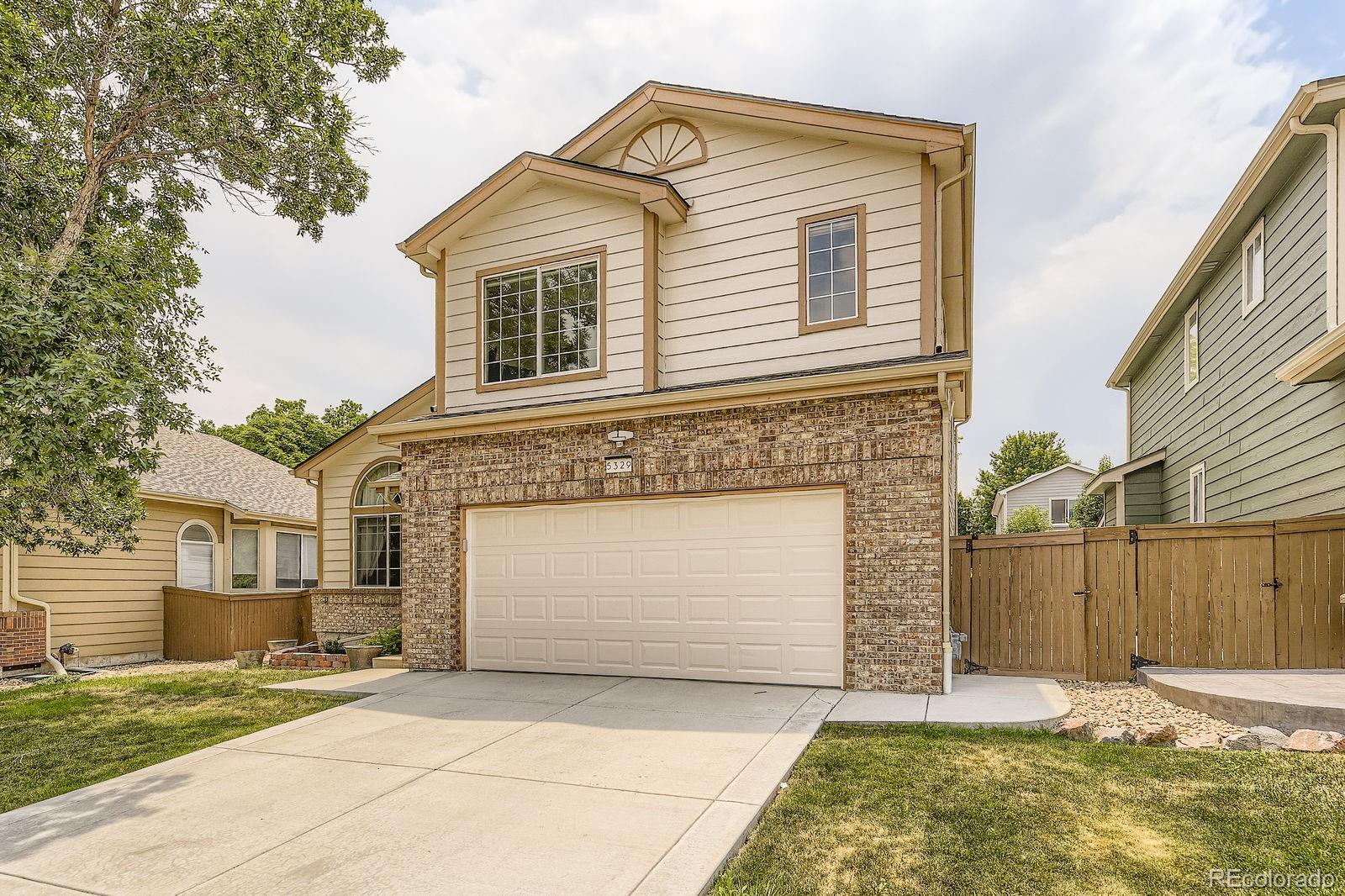 5329 Morning Glory Place Highlands Ranch, CO 80130 - Photo 3 of 28 a front view of a house with a yard and garage