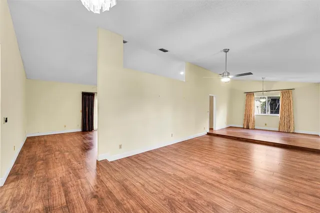 a view of an empty room with a window and wooden floor