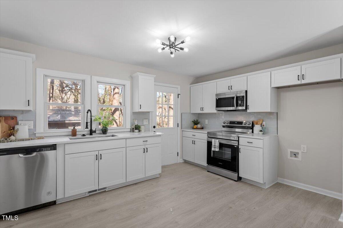 1404 Valley Road Garner, NC 27529 - Photo 3 of 29 a kitchen with stainless steel appliances a sink a stove a refrigerator cabinets and a window