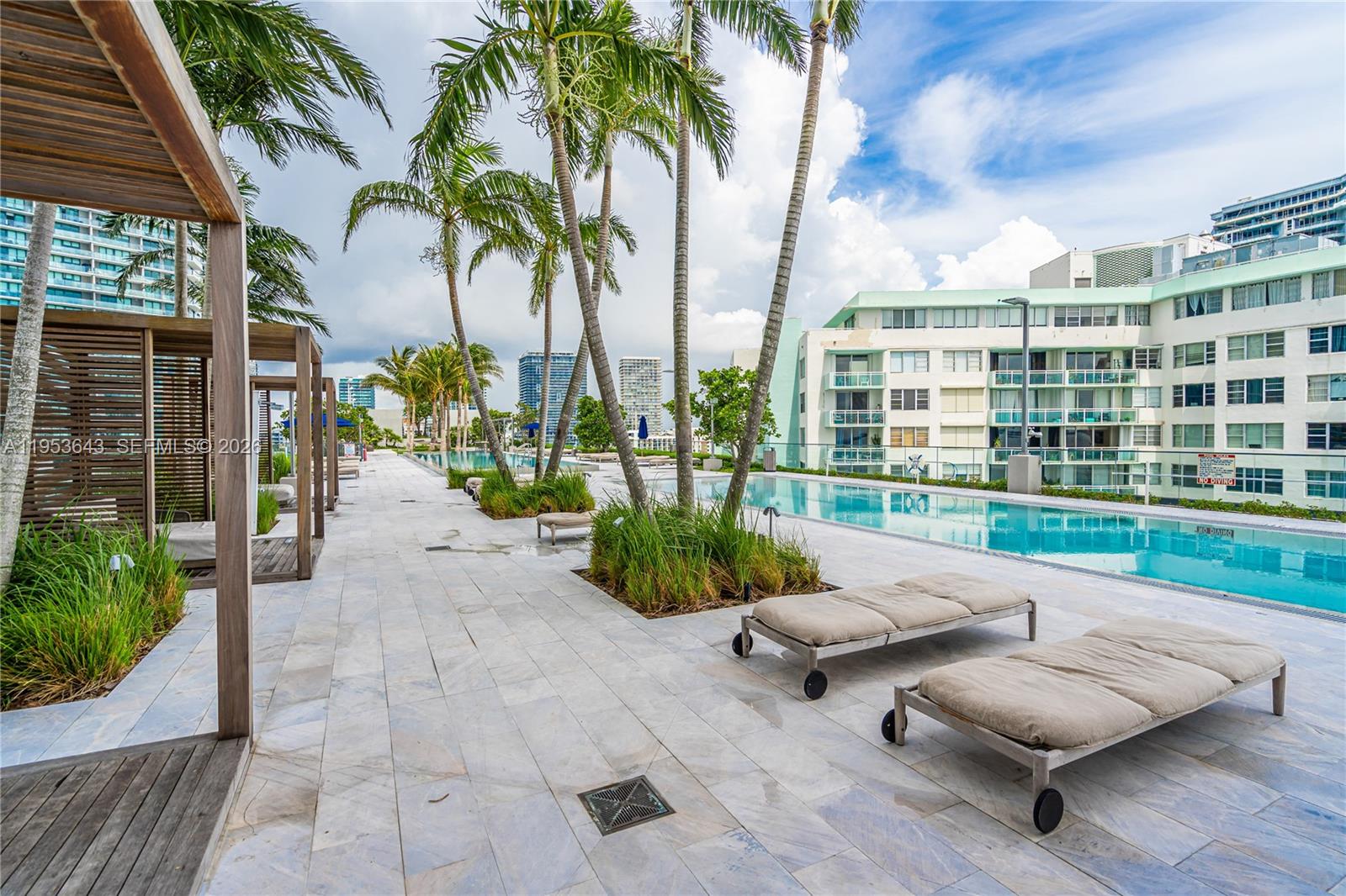 3131 Northeast 7th Avenue, Unit 3704 Miami, FL 33137 - Photo 50 of 61 a view of a patio with couches and a table and chairs with wooden floor and fence