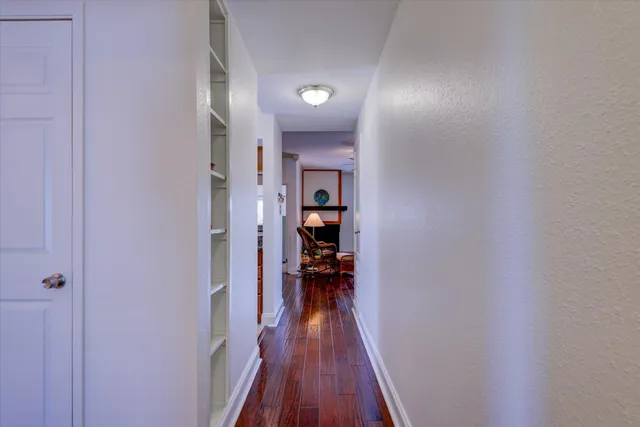 a view of a hallway with wooden floor and a bathroom