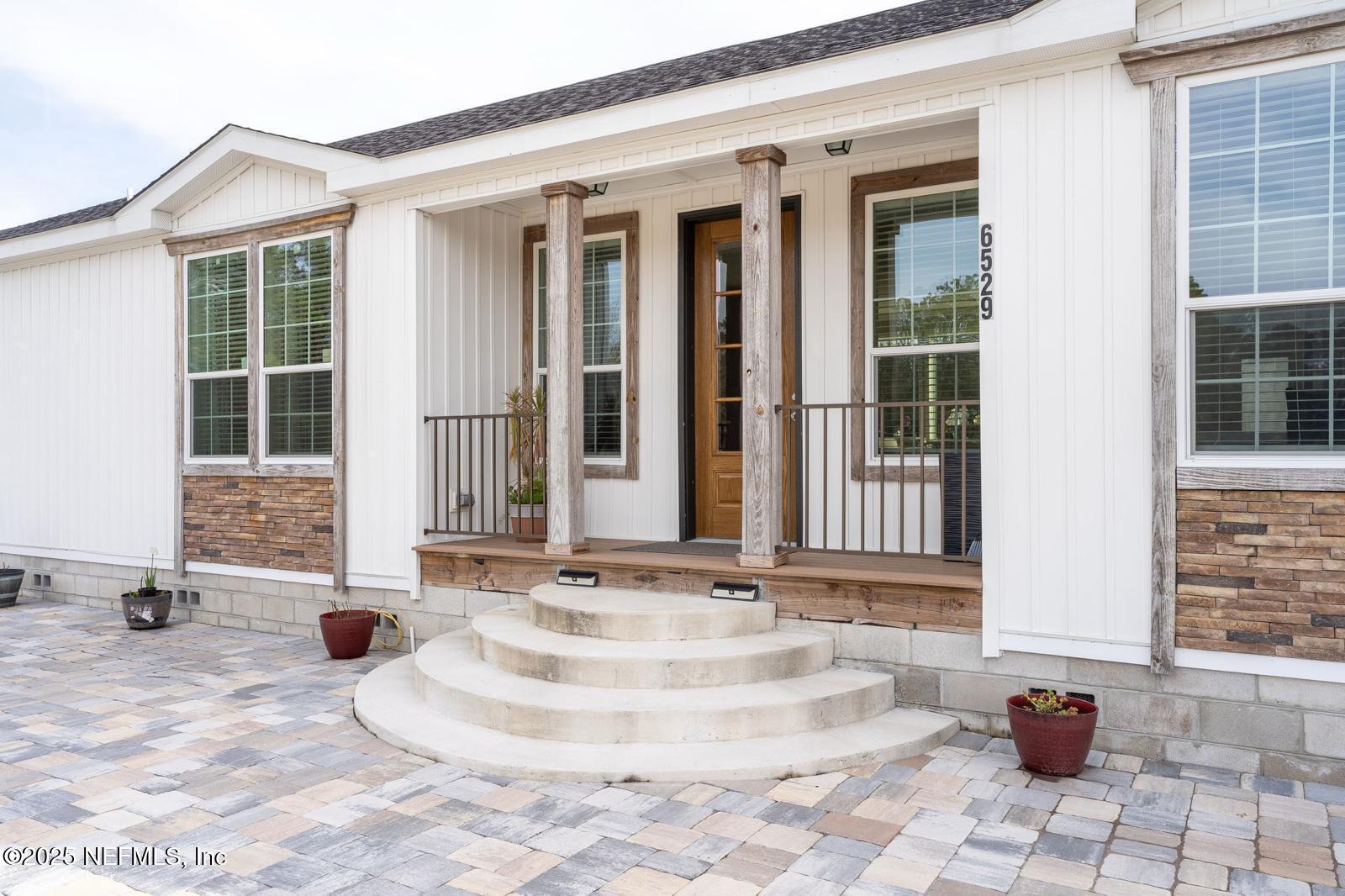 6529 County Road 121 Bryceville, FL 32009 - Photo 4 of 39 a view of a brick house with potted plants and wooden bench