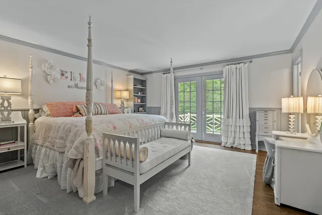 a spacious bedroom with a bed a chandelier and large window
