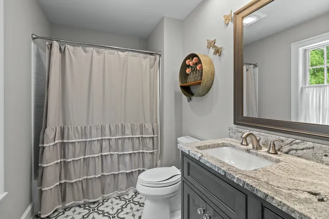 a bathroom with a granite countertop sink and a toilet