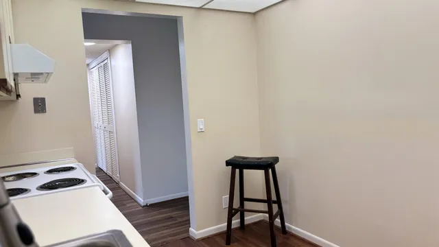 a view of a hallway with wooden floor and a bathroom