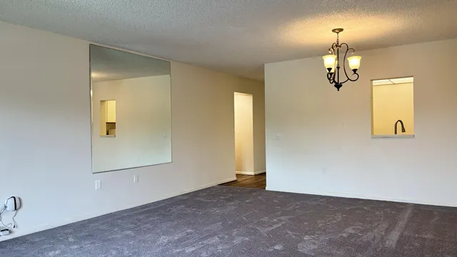 an empty room with a chandelier fan and wooden floor