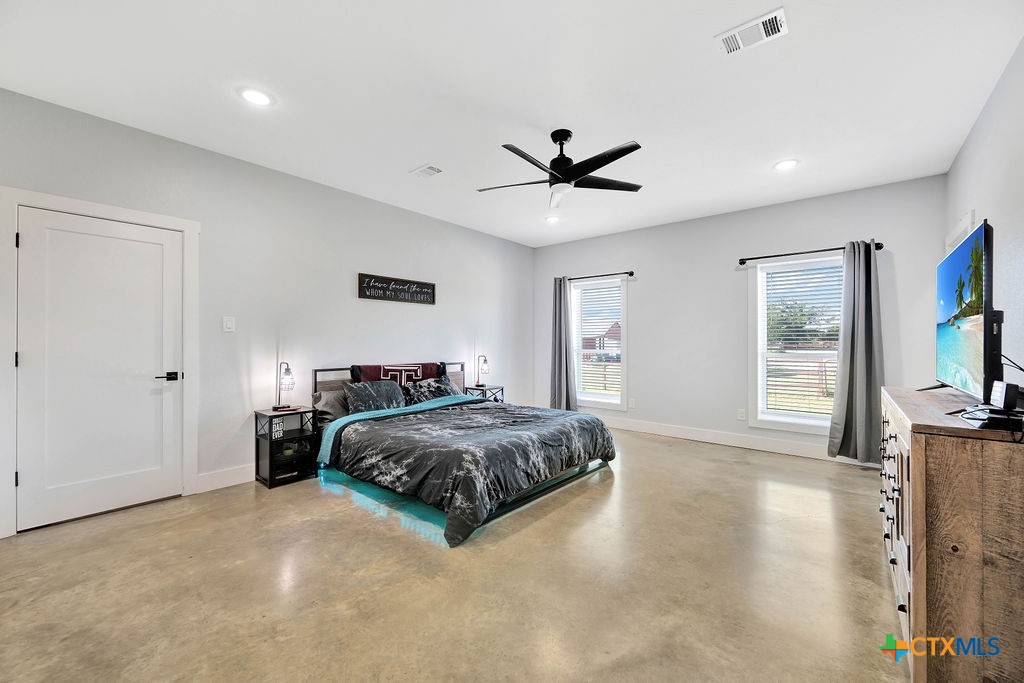 6887 Smith Dairy Road Belton, TX 76513 - Photo 24 of 48 a spacious bedroom with a bed a flat screen tv and a large window