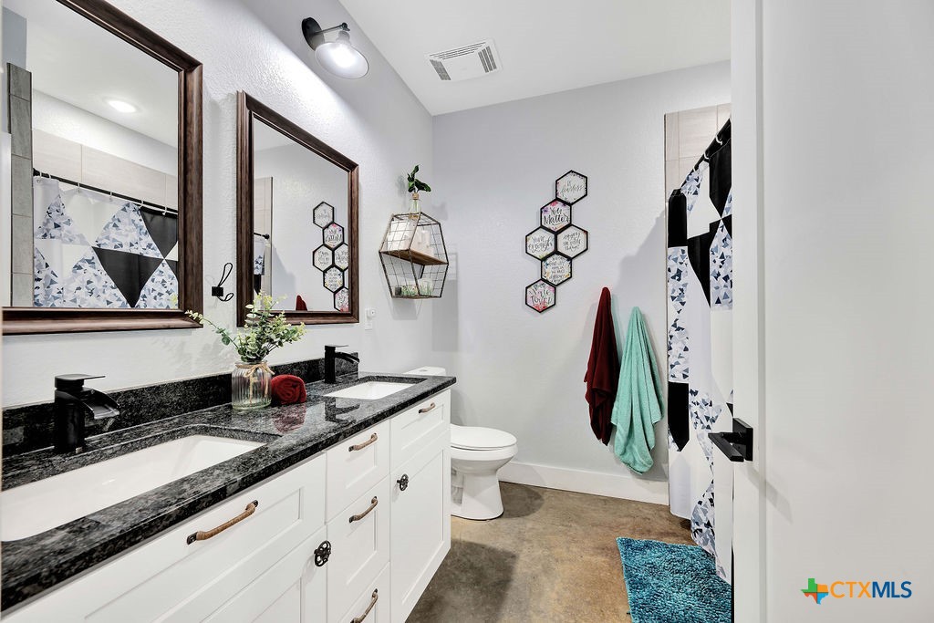 6887 Smith Dairy Road Belton, TX 76513 - Photo 8 of 48 a bathroom with a granite countertop sink a toilet and a mirror