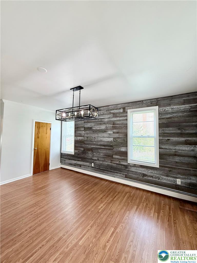 5540 Main Street Whitehall, PA 18052 - Photo 13 of 53 Laminate flooring complements the distinctive wood-paneled accent wall, creating a captivating interior.