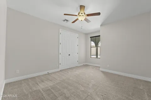 an empty room with ceiling fan and window
