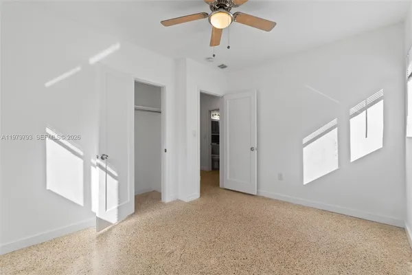 an empty room with a window and a fan