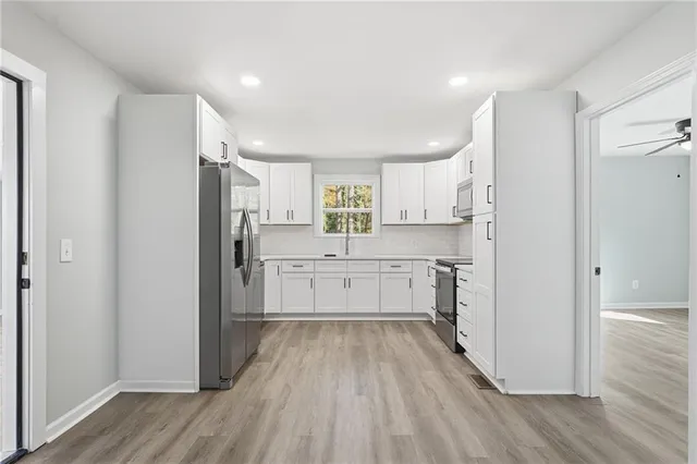 a kitchen with white cabinets and stainless steel appliances