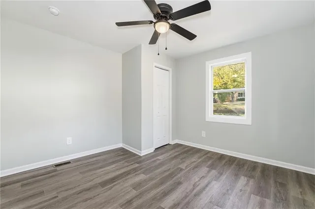 a view of an empty room with a window and wooden floor