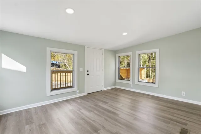 a view of an empty room with a window and wooden floor