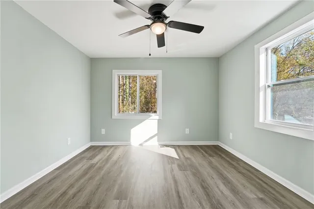 a view of empty room with wooden floor and ceiling fan