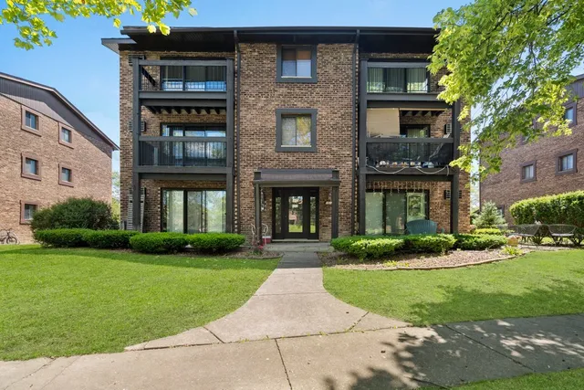 a front view of a brick house with a yard and plants