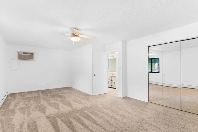 an empty room with closet and a ceiling fan