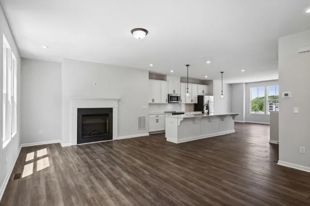 a large white kitchen with kitchen island a fireplace wooden floor and a window