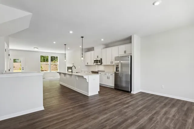 a large white kitchen with wooden floor and stainless steel appliances