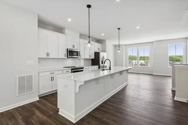a large kitchen with stainless steel appliances kitchen island a large counter top and wooden floors