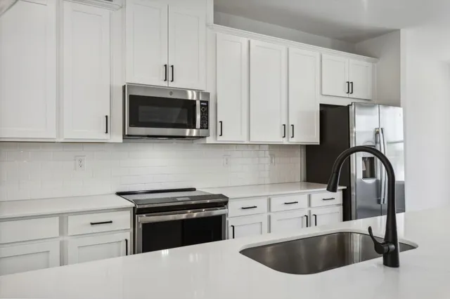 a kitchen with granite countertop white cabinets and stainless steel appliances