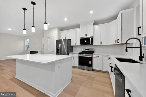 a kitchen with kitchen island a white counter top space cabinets and stainless steel appliances