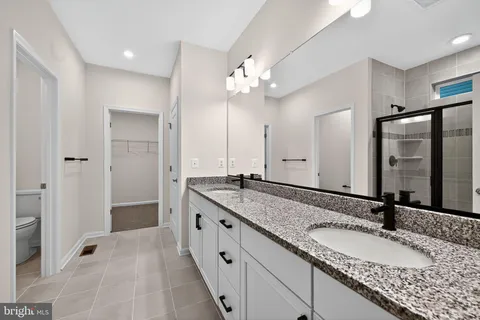 a bathroom with a granite countertop double vanity sink and mirror