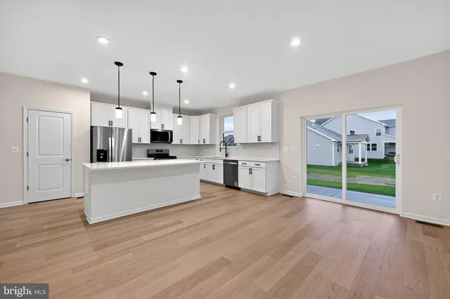 a large kitchen with kitchen island a stove a refrigerator a sink and a oven with wooden floor