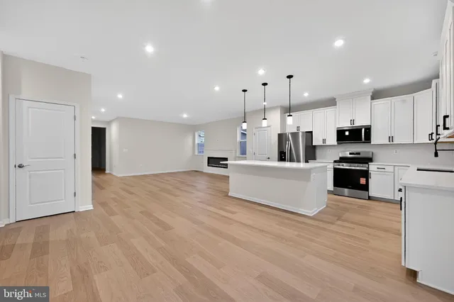 a large white kitchen with kitchen island a sink a stove and a refrigerator