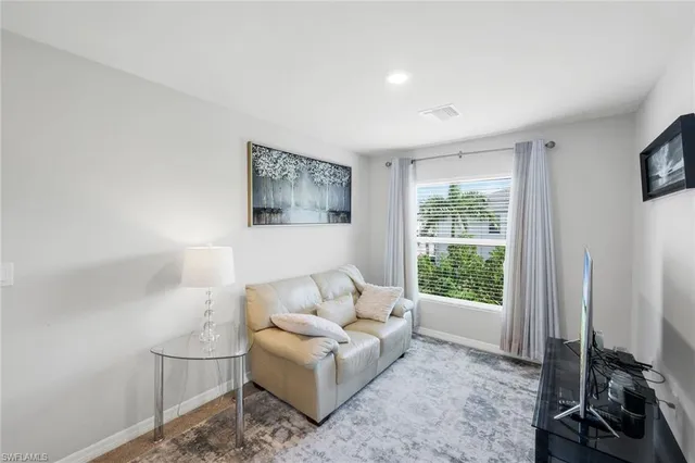 a living room with furniture a flat screen tv and a window