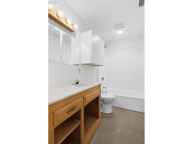 an empty room with windows and chandelier fan