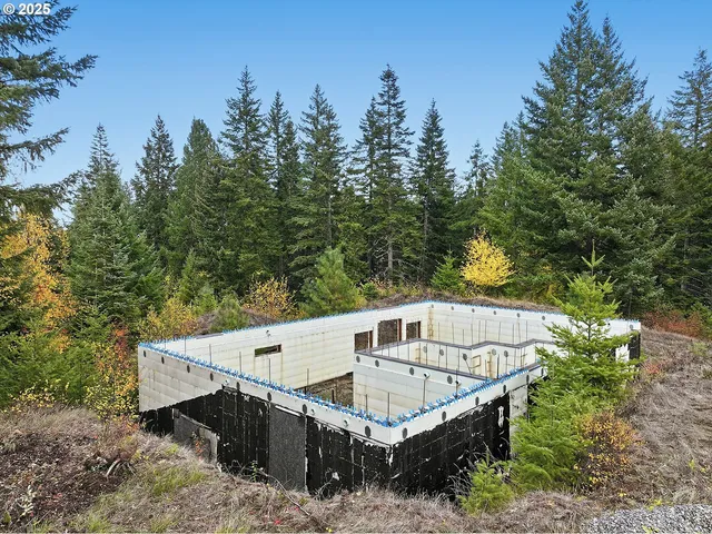 a view of a white house next to a yard with large trees