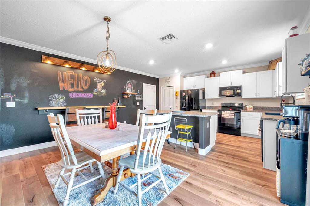 3737 Copperspring Boulevard New Port Richey, FL 34653 - Photo 30 of 61 a open kitchen with stainless steel appliances granite countertop a stove top oven a sink a dining table and chairs with wooden floor