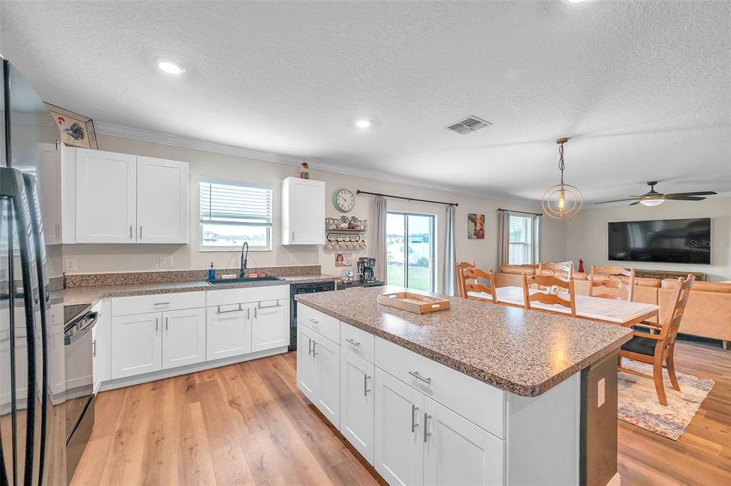 3737 Copperspring Boulevard New Port Richey, FL 34653 - Photo 38 of 61 a large kitchen with granite countertop a stove top oven a sink a dining table and chairs