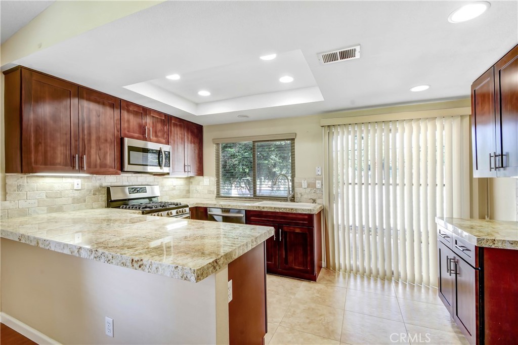7858 Peralta Road Rancho Cucamonga, CA 91730 - Photo 2 of 14 a kitchen with a stove a sink a microwave a counter top space and cabinets