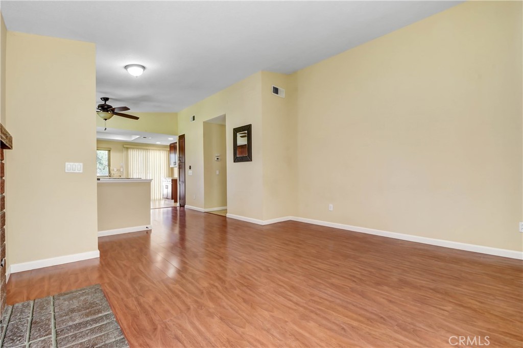 7858 Peralta Road Rancho Cucamonga, CA 91730 - Photo 6 of 14 a view of an empty room with wooden floor and a kitchen