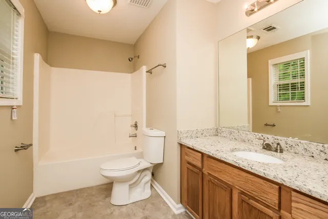 a bathroom with a granite countertop toilet a sink and a bathtub