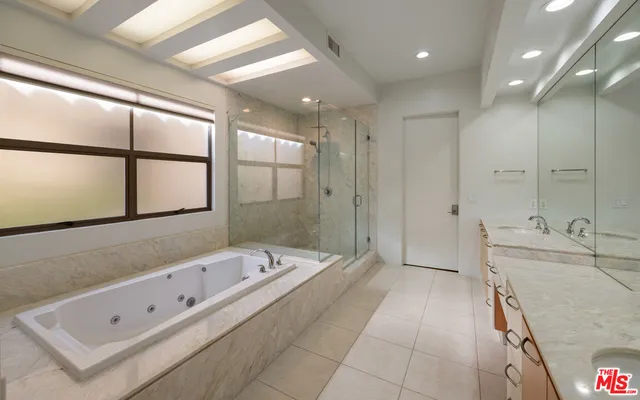 a large spacious bathroom with a tub a double vanity sink and mirror