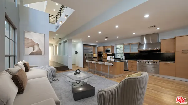 a living room with furniture kitchen view and a wooden floor