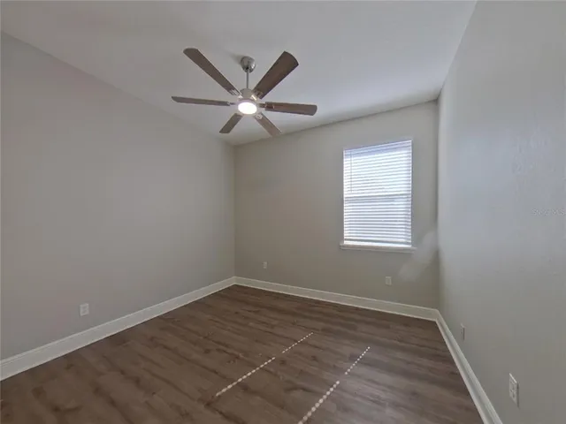 an empty room with a window and ceiling fan