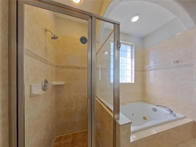 a bathroom with a tub a shower and a mirror