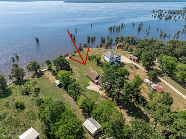 an aerial view of a house with a yard and lake view
