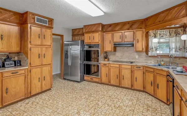 a kitchen with stainless steel appliances granite countertop a refrigerator a stove and a sink with cabinets