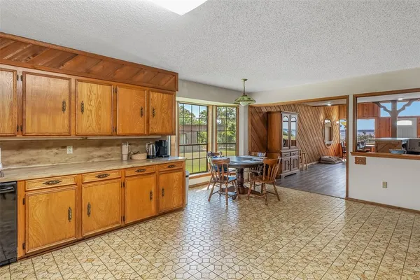a dining hall with stainless steel appliances granite countertop a stove a sink a dining table and chairs with wooden floor