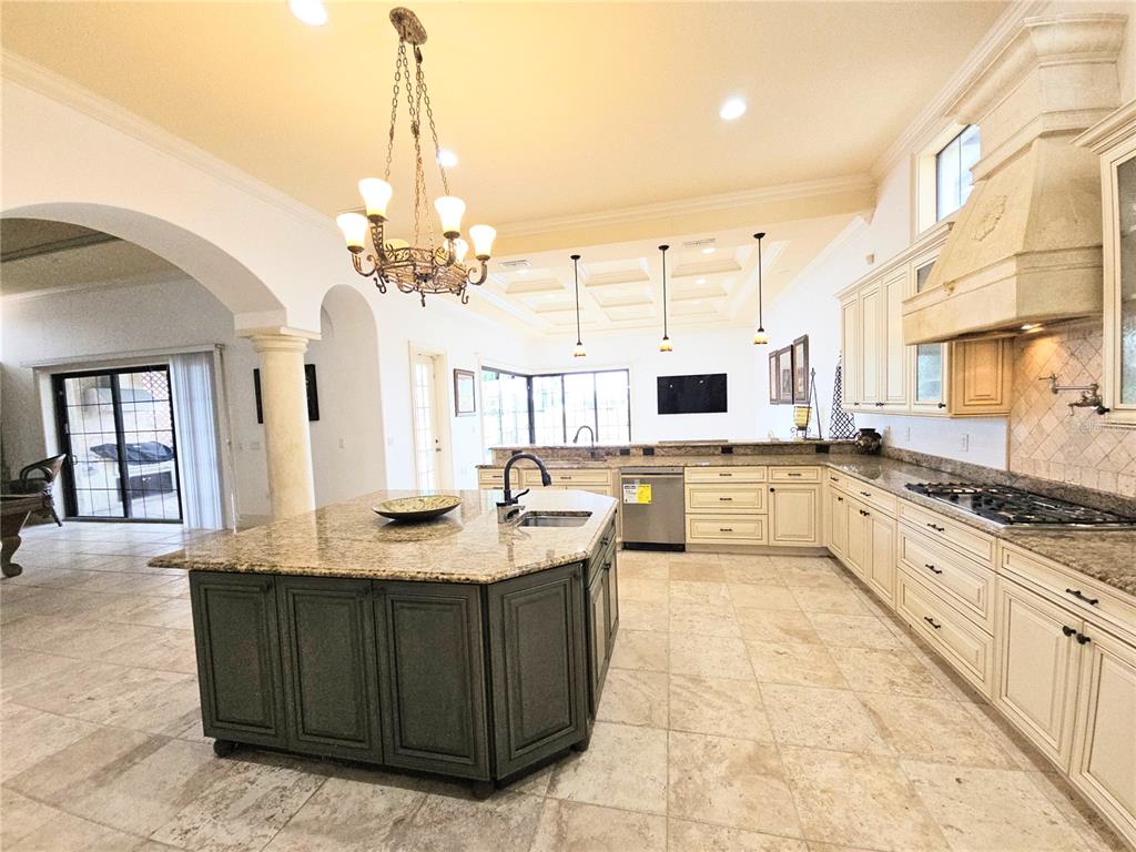 420 Muirfield Loop Reunion, FL 34747 - Photo 10 of 60 a large kitchen with kitchen island granite countertop a stove a sink dishwasher and white cabinets with wooden floor