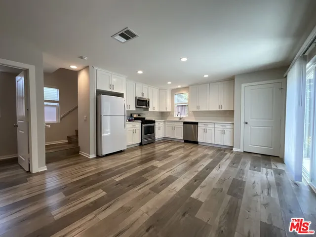 a view of kitchen view wooden floor stainless steel appliances and cabinets