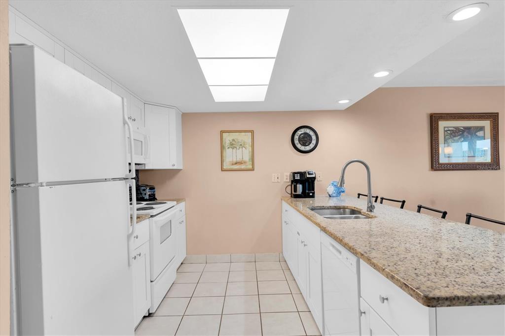 19610 Gulf Boulevard, Unit 308 Indian Rocks Beach, FL 33785 - Photo 11 of 41 a large white kitchen with a sink a stove a refrigerator and cabinets