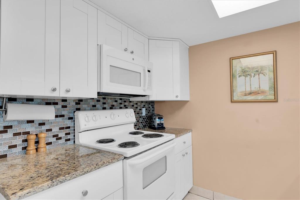 19610 Gulf Boulevard, Unit 308 Indian Rocks Beach, FL 33785 - Photo 13 of 41 a kitchen with a sink a stove and white cabinets