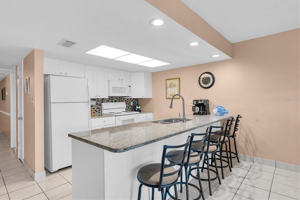 19610 Gulf Boulevard, Unit 308 Indian Rocks Beach, FL 33785 - Photo 9 of 41 a kitchen with kitchen island a stove a table and chairs in it